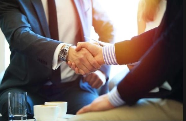 Two business people shaking hands over coffee
